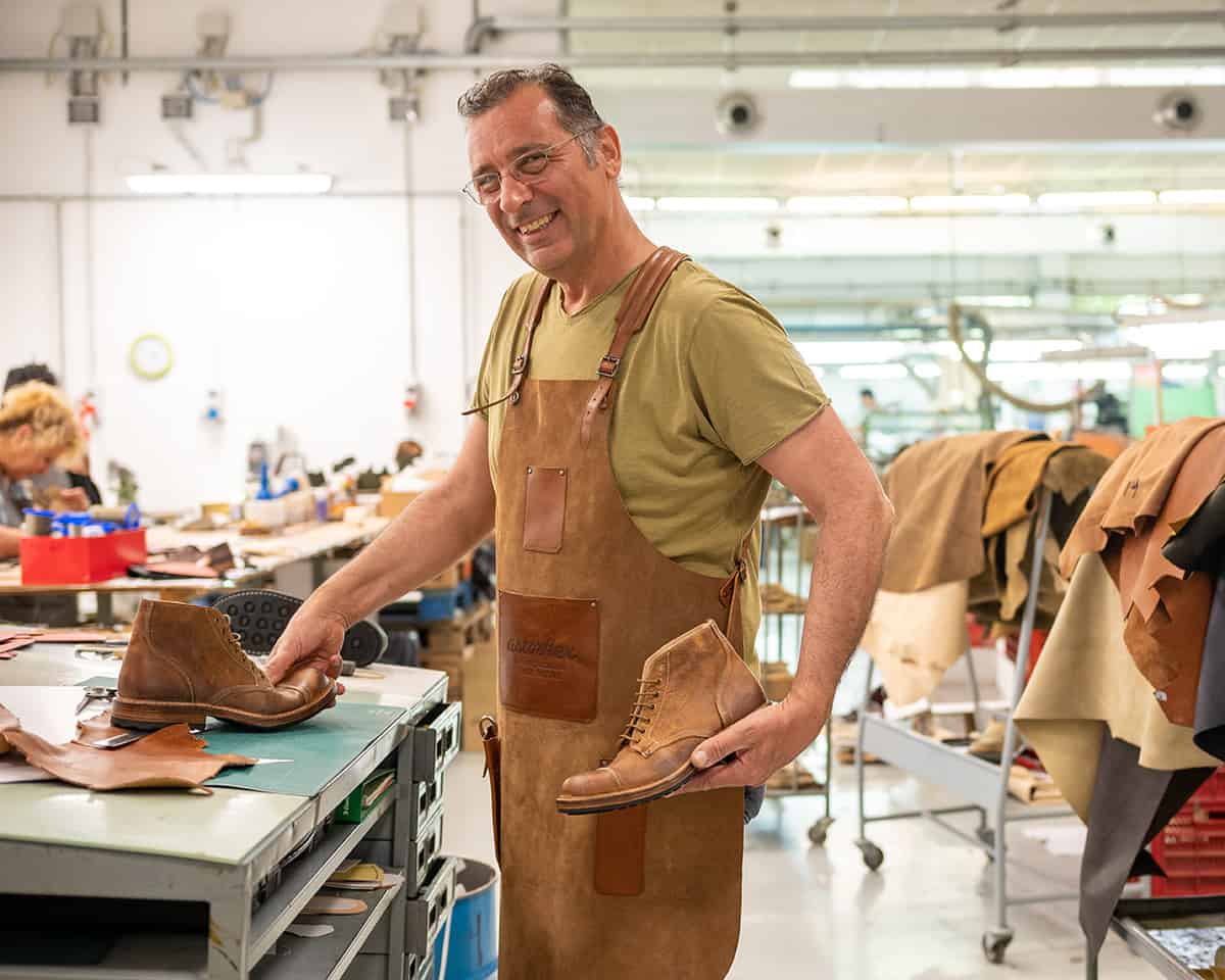A craftsman at the Astorflex factory pause to show a pair of boots he has recently completed making. 